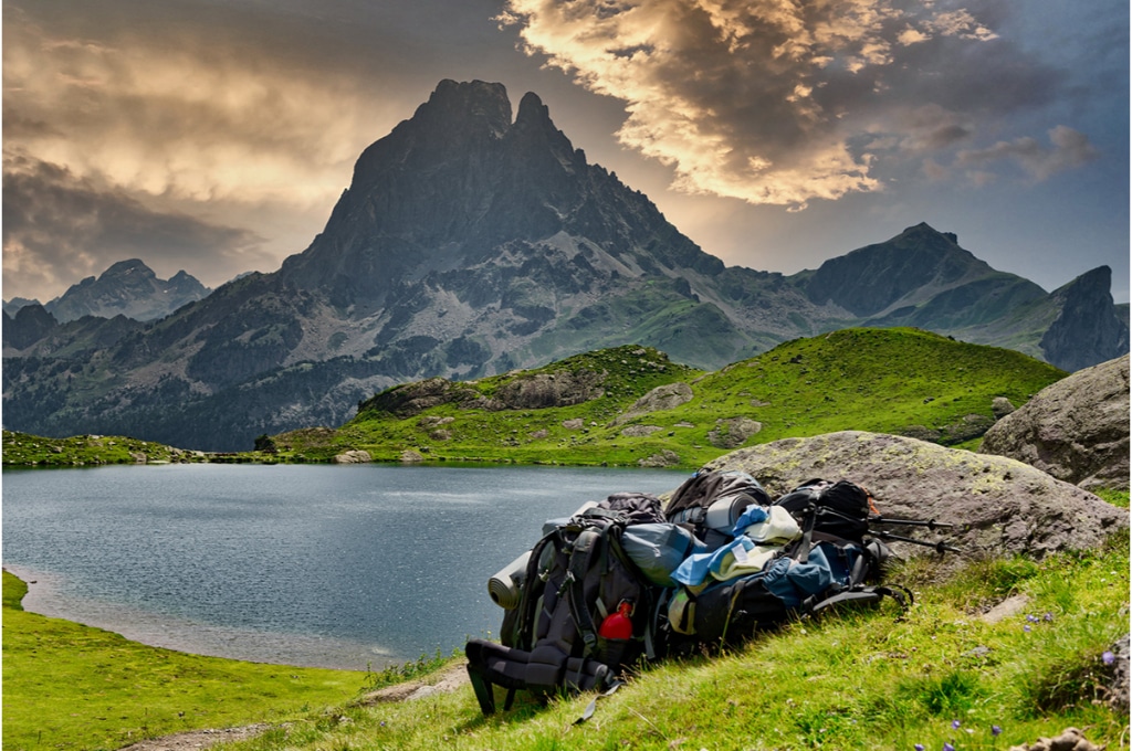 photo d'un sac de randonneur surchargé posé devant le Pic du Midi d'Ossau situé devant un lac.