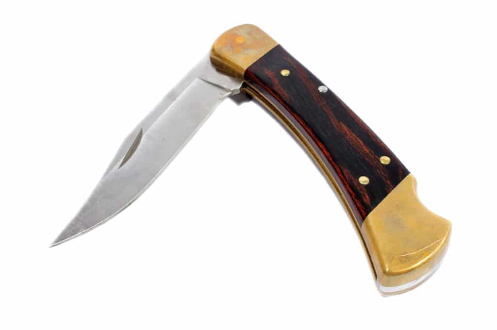 couteau de poche pliant sur un fond blanc. la lame coupante est à moitié sortie du manche d'un aspect bois.