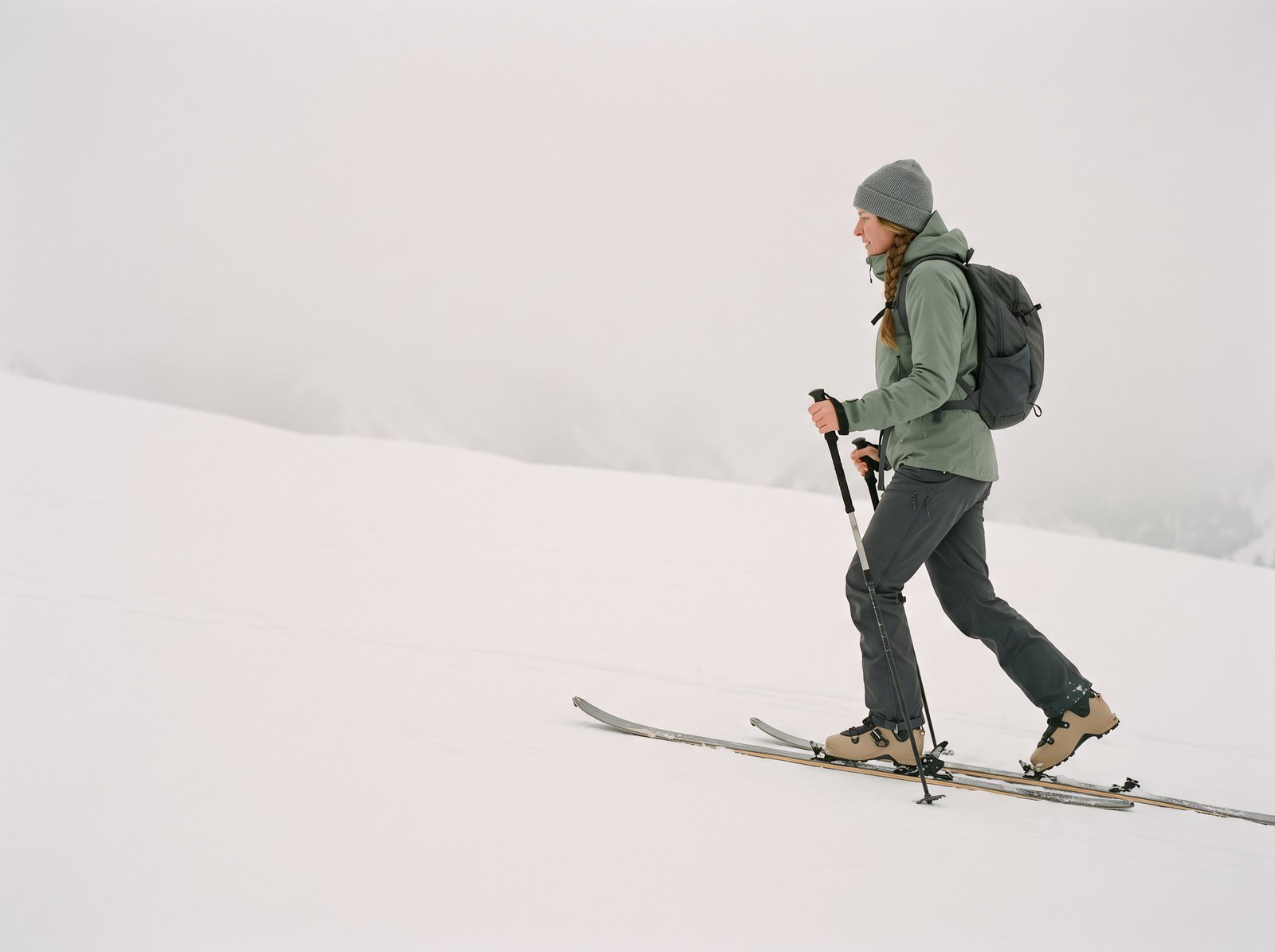 Skieuse de randonnée montant en peaux de phoque sur une pente enneigée des Alpes, le talon gauche décollé de la fixation