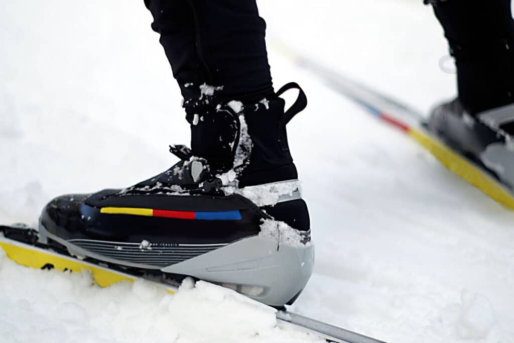 vue rapproché sur des chaussures de ski accrochées à des skis sur la neige.