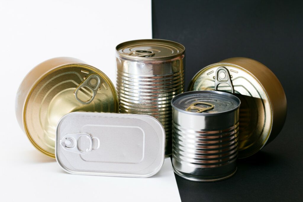 5 boites de conserve en métal sont posées devant un fond blanc et noir