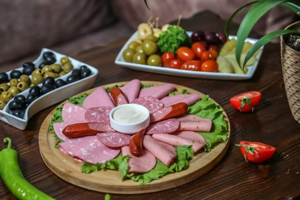 sur une table en bois sont disposées des assiettes de charcuterie, olives vertes et noires.